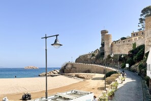 Camino costero con un castillo, playa y un muelle.