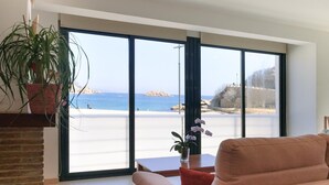 Un salon moderne doté d’une grande fenêtre donnant sur une plage.
