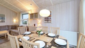 En matplats med ett runt bord för fyra personer, omgiven av trästolar. I bakgrunden finns en soffa och ett litet bord med en lampa.