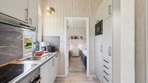 Una cocina estrecha con estufa, lavamanos y una pequeña zona de comedor.