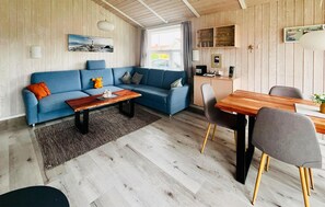 Un soggiorno moderno con un divano blu, un tavolino in legno e un'area pranzo con tavolo e sedie in legno.