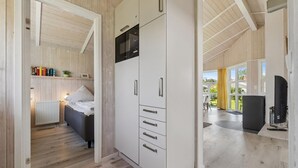 Un dormitorio moderno con cama, mesita de noche y armario con microondas incorporado.