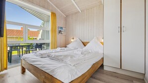 Un dormitorio con cama de madera, un armario y vistas al exterior.
