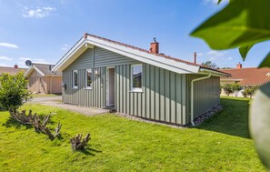 Une maison de plain-pied avec un toit en pente, une cheminée bien visible et un petit porche à l’avant.