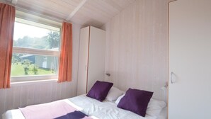 A bedroom with a bed, two pillows, a window with curtains, and a view of the outside. - Awesome home in Schönhagen with sauna (Schönhagen)