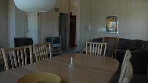 A dining area with a wooden table, chairs, a television, and a sofa. - Awesome home in Schönhagen with sauna (Schönhagen)