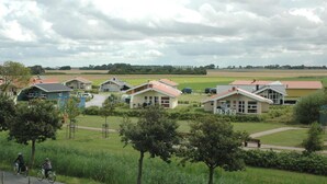Entorno rural con varias casas pequeñas, un sendero pavimentado y ciclistas.