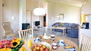 Una sala de estar moderna con un sofá, una mesa de centro y un comedor con una mesa lista para el desayuno.
