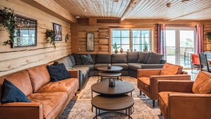A cozy log cabin interior with a sectional sofa, two round tables, and a dining area. - 10 bedroom amazing home in ølen (Ølen)