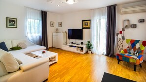 A modern living room with a sofa, a coffee table, a TV, and a colorful chair. - Luxurious home in Dicmo (Dicmo)