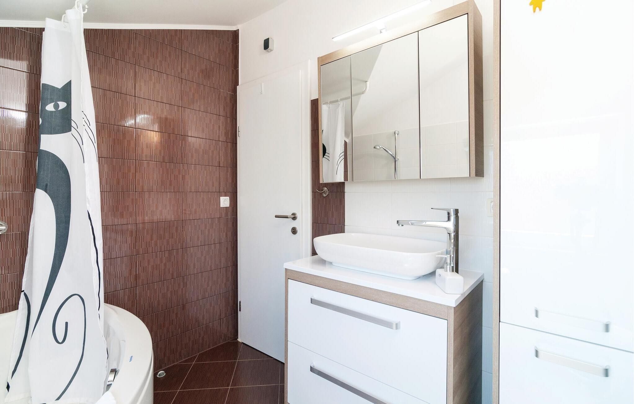 A modern bathroom with a white sink, a mirror above the sink, and a shower curtain with a geometric pattern.