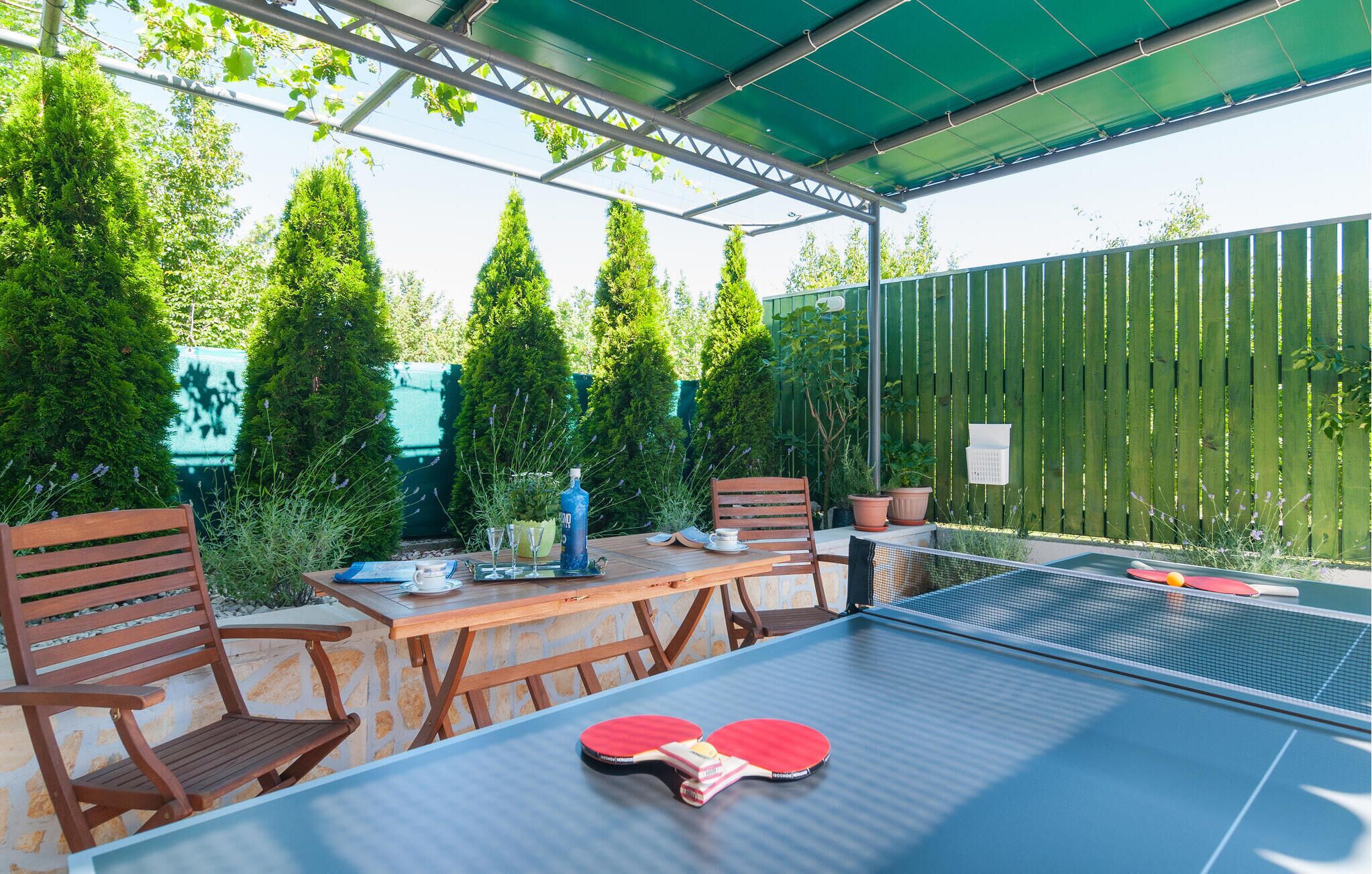 Una mesa de tenis de mesa al aire libre, con sillas y dos paletas de ping pong.