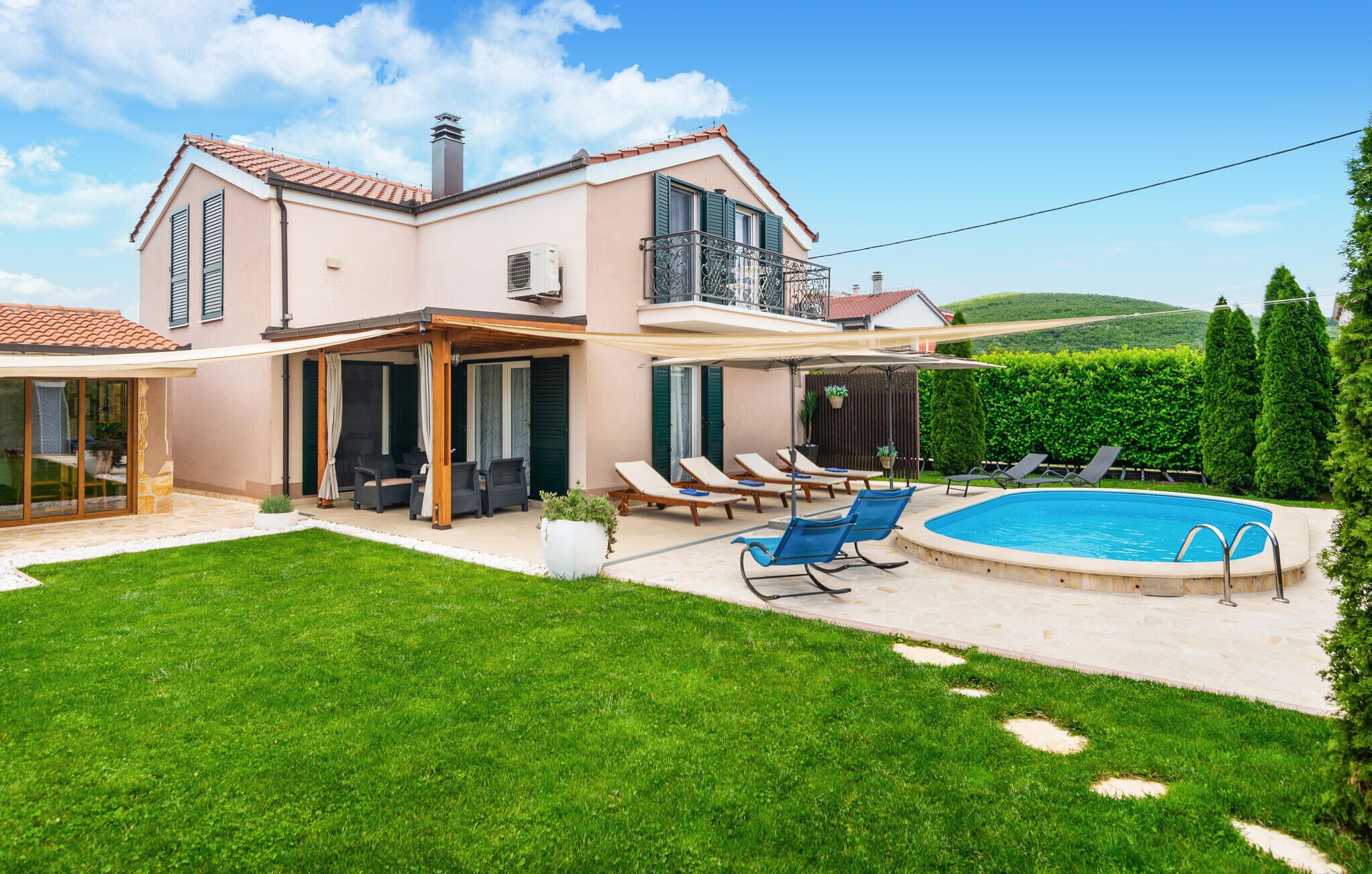 Ein zweigeschossiges Haus mit Swimmingpool, überdachter Terrasse und gepflegtem Rasen.