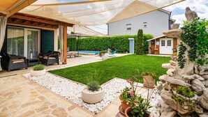 A covered patio with outdoor furniture, a swimming pool, and a well-maintained lawn. - Luxurious home in Dicmo (Dicmo)