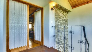 A wooden staircase leading to a bedroom with a stone wall and a metal railing.