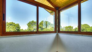 A room with three large windows, a wooden ceiling, and a textured wall.