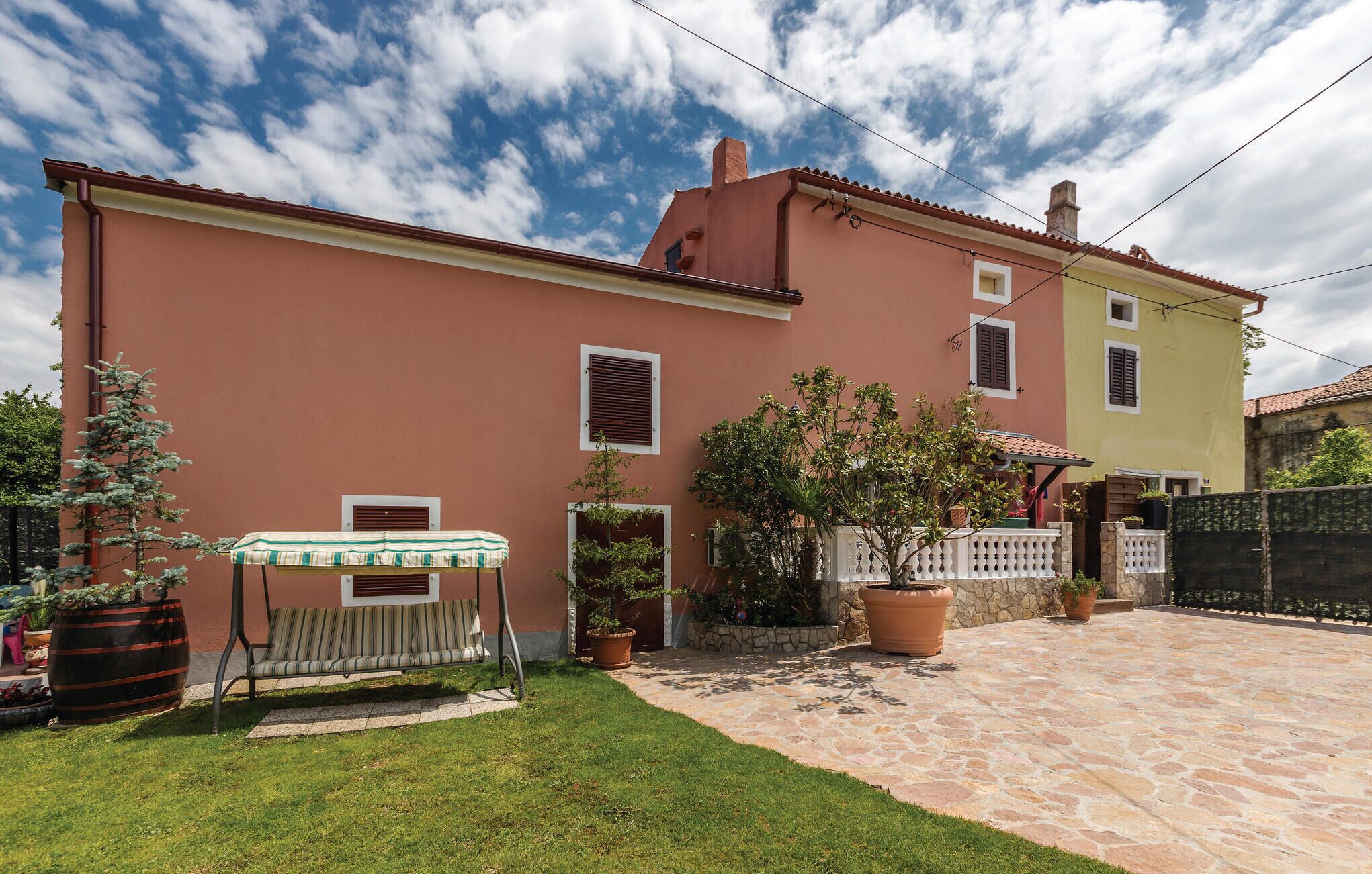A two-story house with a stone patio and a small garden area.
