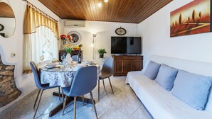 Zona pranzo con un tavolo rotondo, sedie e una TV sullo sfondo.