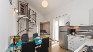 A modern kitchen with a built-in gas stove, a refrigerator, and a dining area with a glass table and chairs. - 2 bedroom pet friendly apartment in Dolac (Dolac)