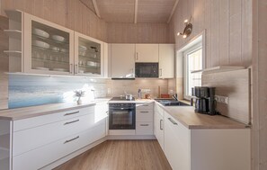 A modern kitchen with white cabinetry, a microwave, a stove, and a coffee maker.