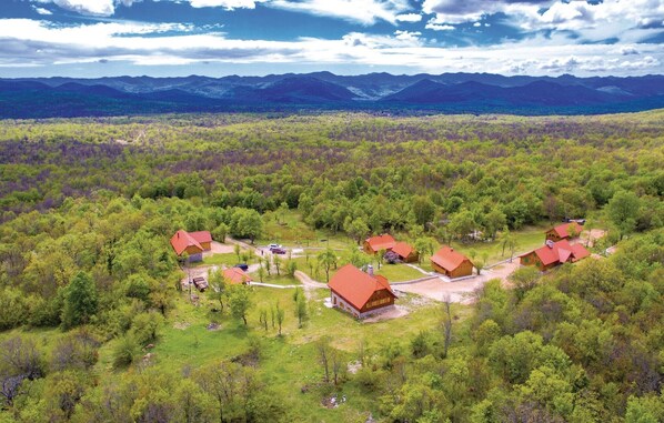 A rural area with several red-roofed cabins surrounded by dense green forest, with mountains in the background. - Pet friendly home in Perusic (Perusic)