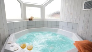 Ein Whirlpool mit zwei Orangensaftgläsern, einem Fenster und einer weißen Fliesenwand.