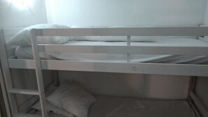 A bunk bed with white bedding and a metal ladder.