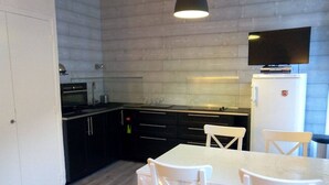 A compact kitchen with dark cabinets, a white countertop, and a built-in TV.