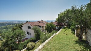 A house with a tiled roof, surrounded by greenery and a stone pathway.