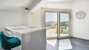 A modern apartment with a balcony, a dining area, and a view of the city.