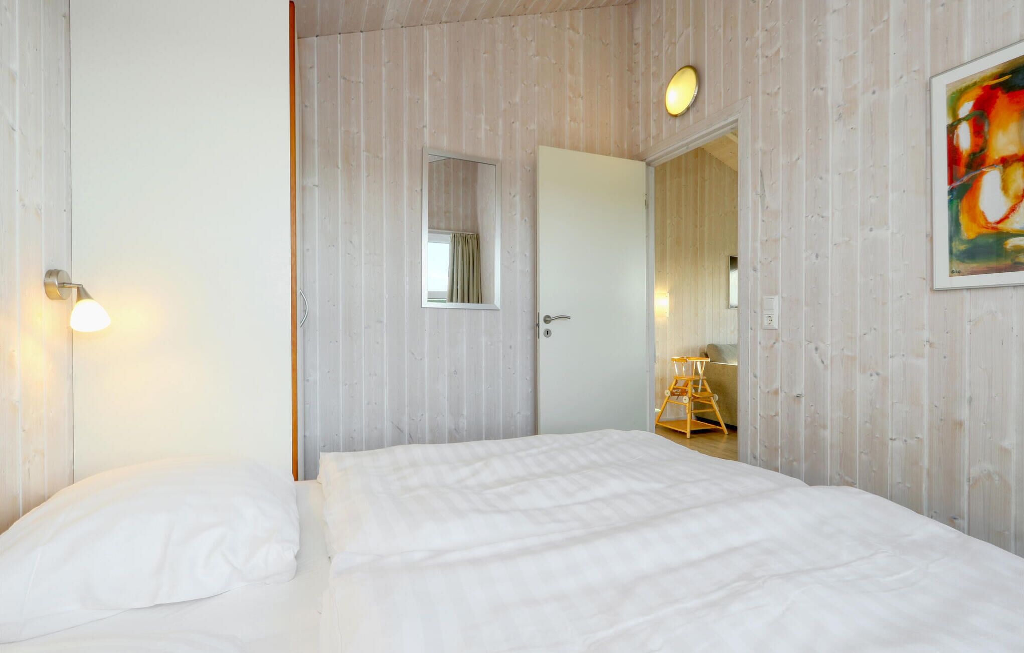 Un dormitorio con cama, puerta, espejo y un cuadro en la pared.