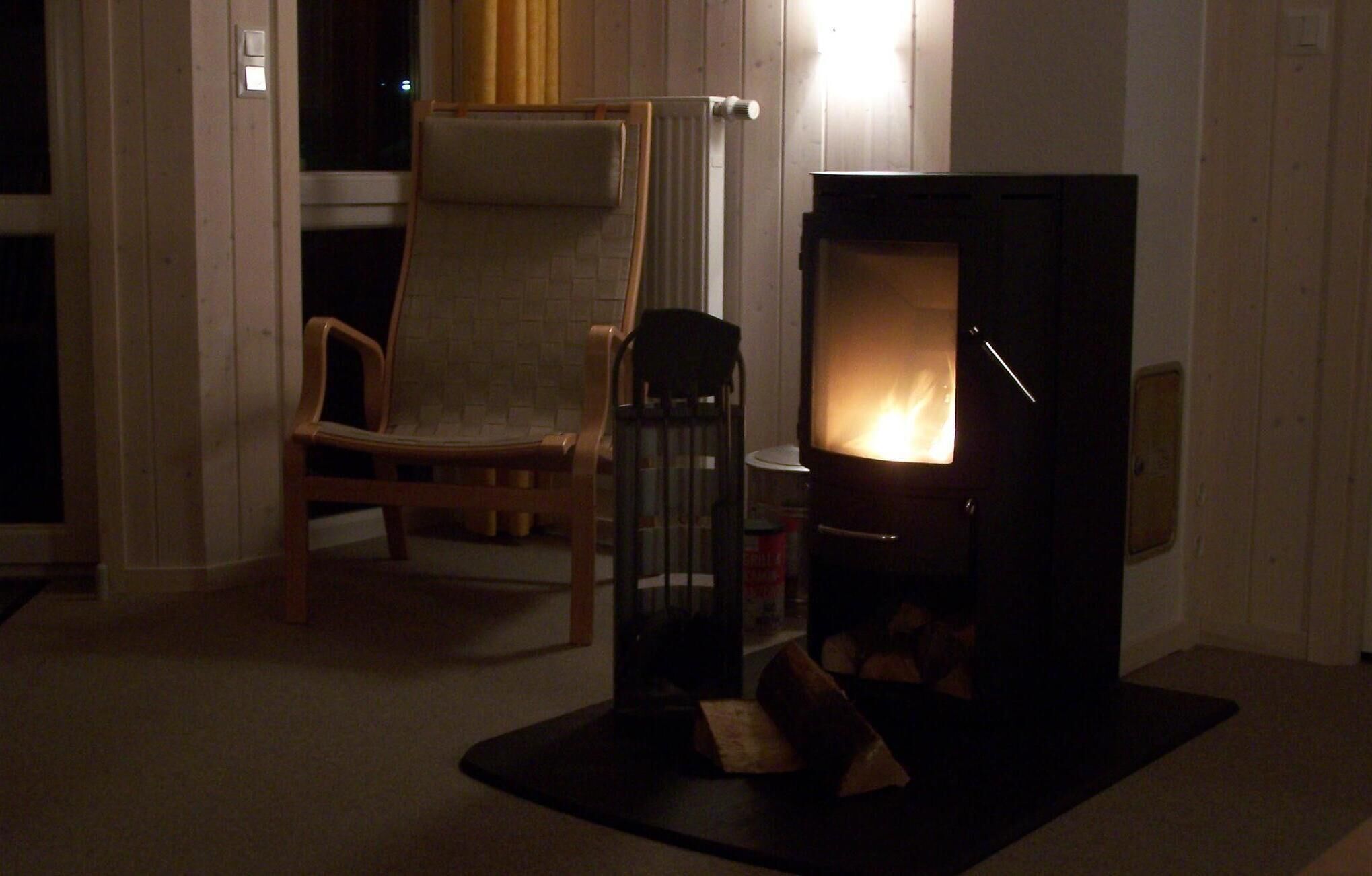 Una sala de estar acogedora con chimenea, una silla de madera y un radiador.