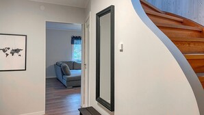 Ein Flur mit einer Holztreppe, einem grauen Sofa im Hintergrund und einer an der Wand aufgehängten Weltkarte.