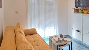 A living room with a sofa, a small table, and a TV on a shelf. - 1 bedroom lovely apartment in Klek (Klek)