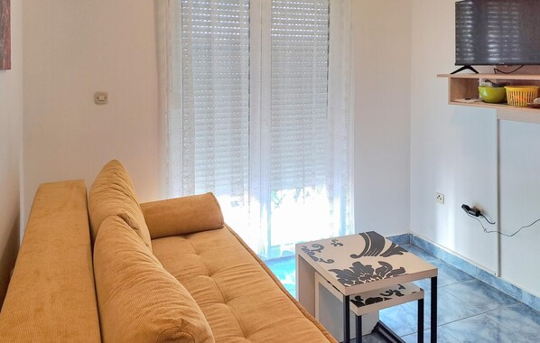 A living room with a sofa, a small table, and a TV on a shelf.