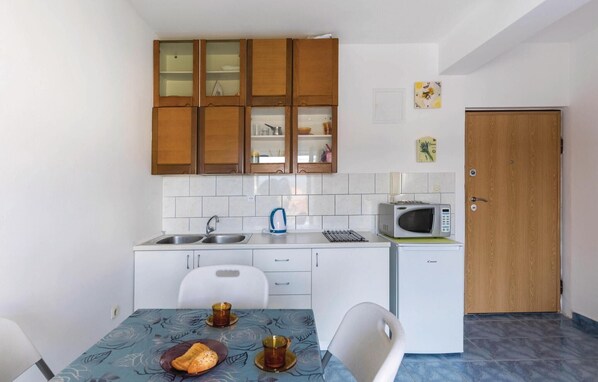 Una cucina compatta con mobili in legno, un forno a microonde, un bollitore e un piccolo frigorifero.