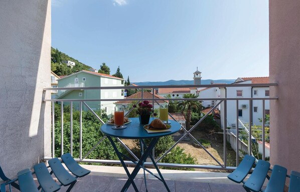 Un balcón con una mesa lista para el desayuno, con vistas a una zona residencial con casas y una iglesia.