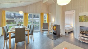 Un interior moderno con comedor, chimenea, cama y televisión.