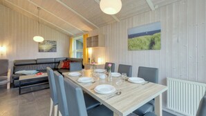 Un comedor con una mesa larga dispuesta para cuatro personas, un sofá y un radiador.