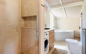 A compact bathroom with a washing machine, a sink, and a toilet. - Awesome home in Schönhagen with sauna (Schönhagen)