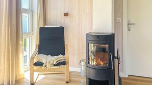Une pièce avec un poêle à bois noir, une chaise bleue avec un coussin blanc et un plancher en bois.