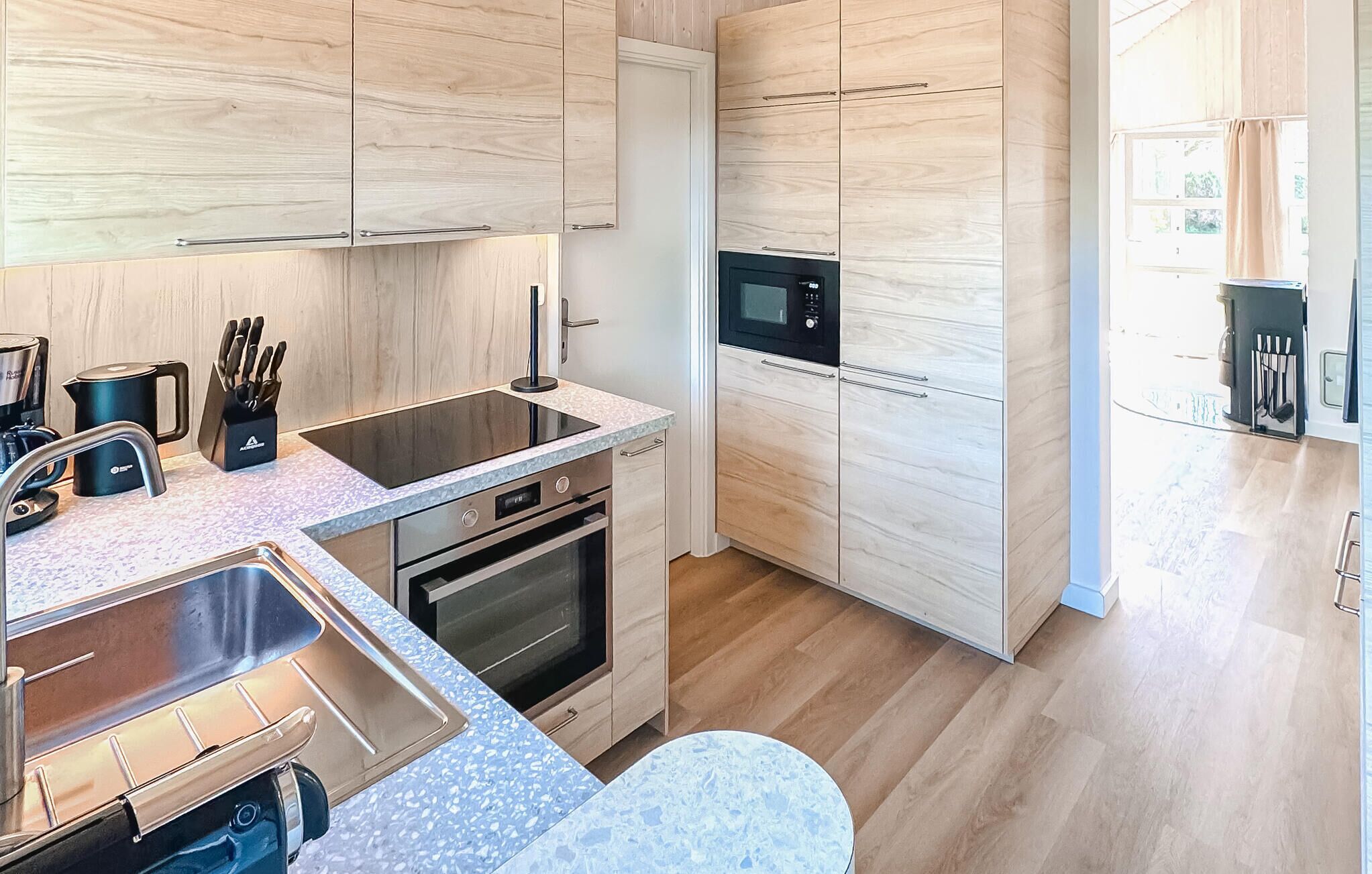 Une cuisine moderne avec des meubles en bois, un four encastré, un four à micro-ondes et un évier.