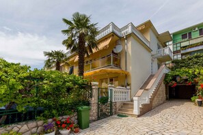 A two-story building with a balcony, a staircase, and a stone-paved courtyard.