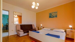 A bedroom with a bed, a sofa, a nightstand, a mirror, and a painting on the wall.