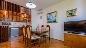 A compact living space with a dining area, kitchen, and entertainment unit.