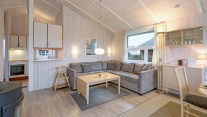Un espacio habitable compacto con kitchenette, un sofá, una mesa de comedor y una silla.