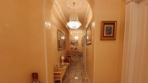 A hallway with marble flooring, a chandelier, framed artwork, and a telephone. - FD Luxury Rooms (Verona)