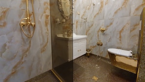 A bathroom with a marble wall, a gold showerhead, a white sink, and a gold toilet. - FD Luxury Rooms (Verona)