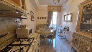 A kitchen with a gas stove, microwave, and a dining area with a table and chairs. - FD Luxury Rooms (Verona)