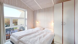 A bedroom with a bed, a wardrobe, and a window with a view of the outdoors. - Friedrichskoog-Strandpark 16 (Friedrichskoog)